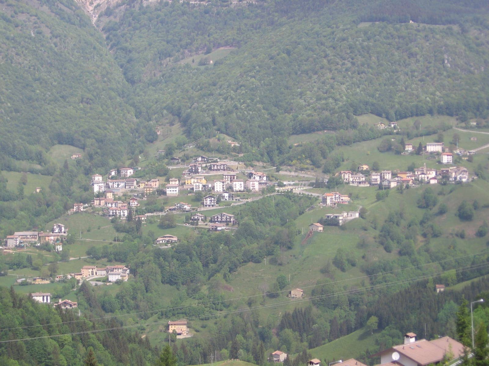 Le case di Zorzone, frazione di Oltre il Colle, allineate tra i prati e i boschi del versante